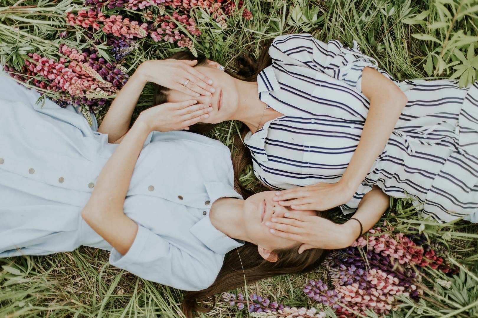 Dwie siostry leżą na łące wśród kwiatów